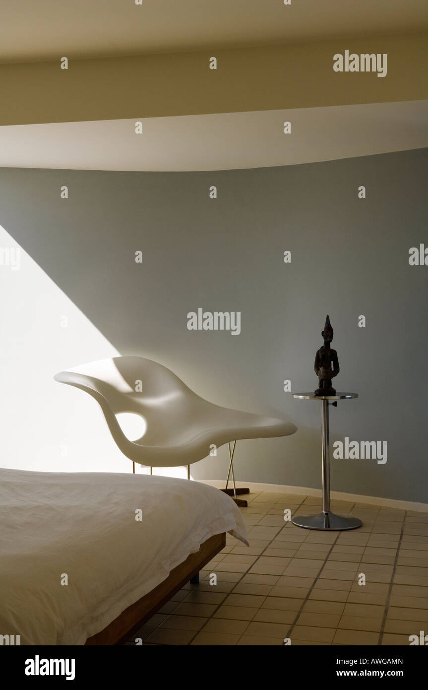 view of bedroom with tiled floor, Eames chair and tribal figurine Stock Photo