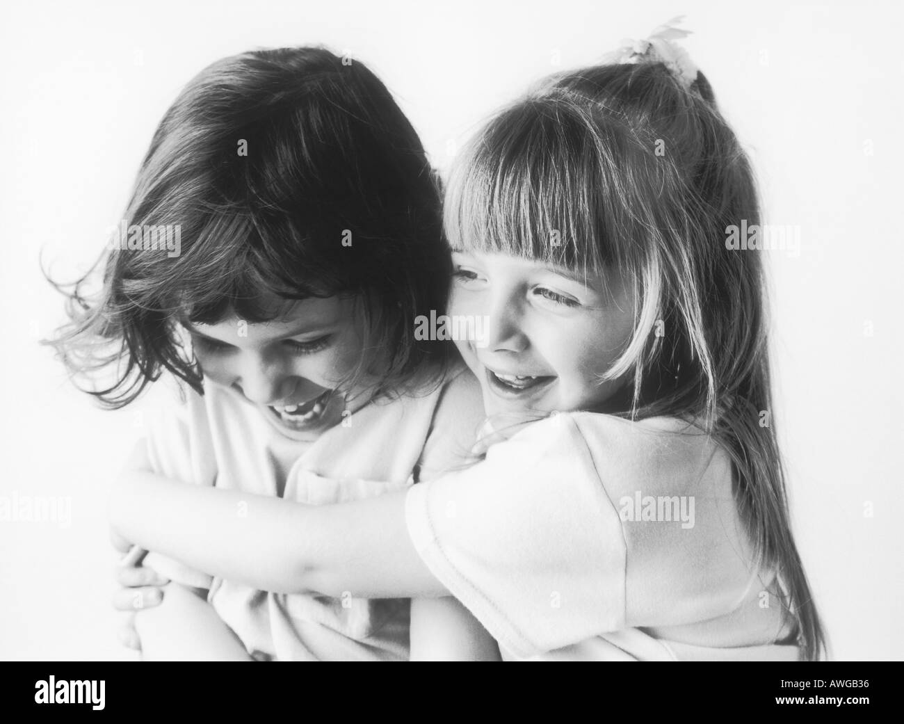 Two young girls one hugging the other Stock Photo