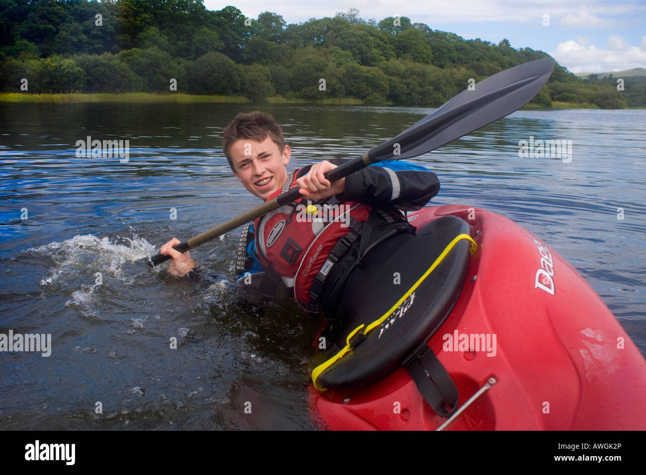 Caucasian teenage boy in a red playboat performing a kayak roll on ...