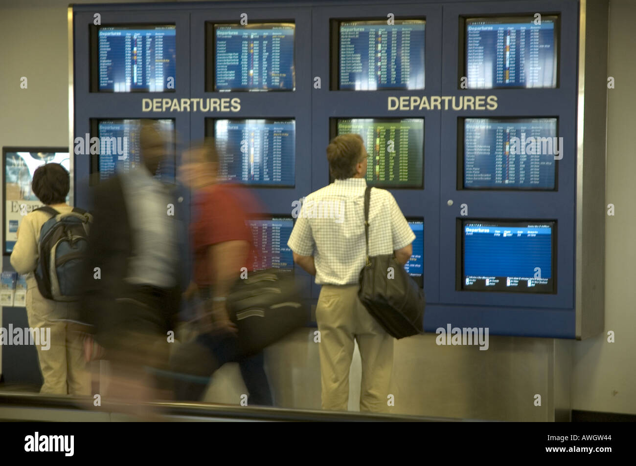 Hurried travelers pass airline schedules in Detroit, Michigan. Stock Photo