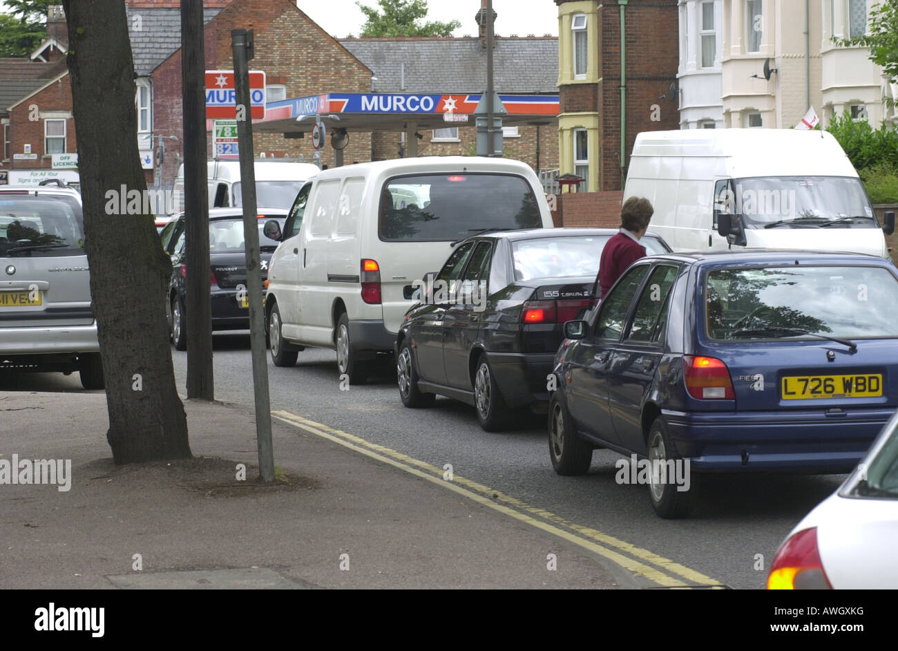 A woman crooses the road through a heavy traffic queue caused by bus lane works on the A6 in Bedford UK Stock Photo