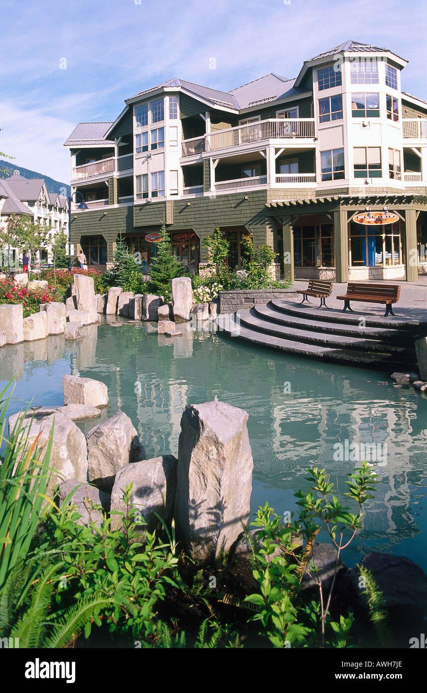 Canada, Pacific Northwest, British Columbia, Whistler, tranquil pond in village, surrounded by modern wooden buildings and shops Stock Photo