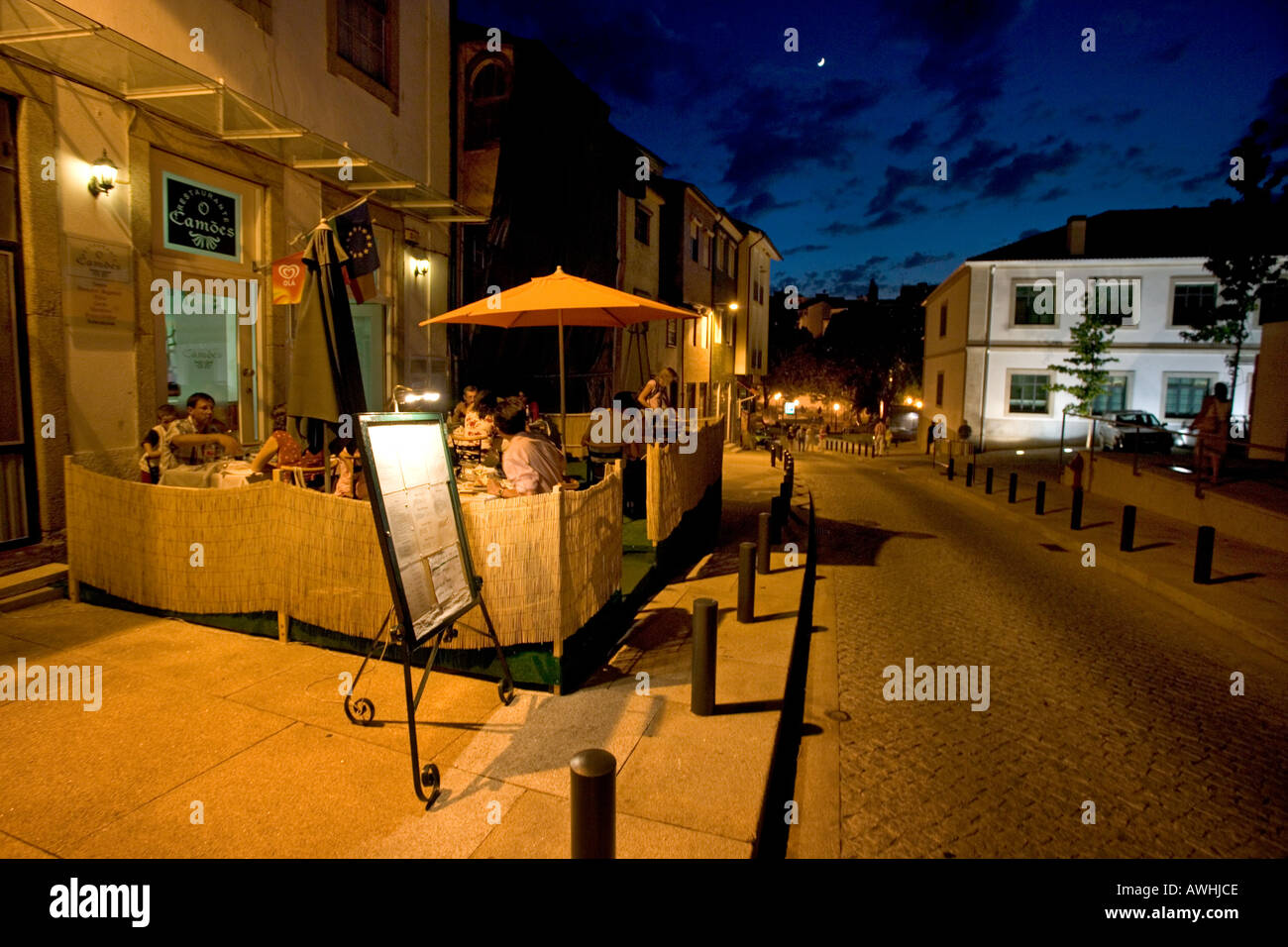 Residents and tourists have a late dinner at a restaurant with outdoor tables in the center of the fortified city of Bragança. Stock Photo