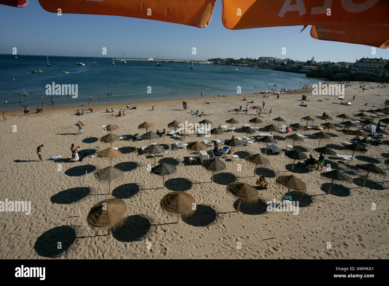 Thatched umbrellas make pools of shade on the beach named Praia da Rainha in the city of Cascais Portugal Stock Photo