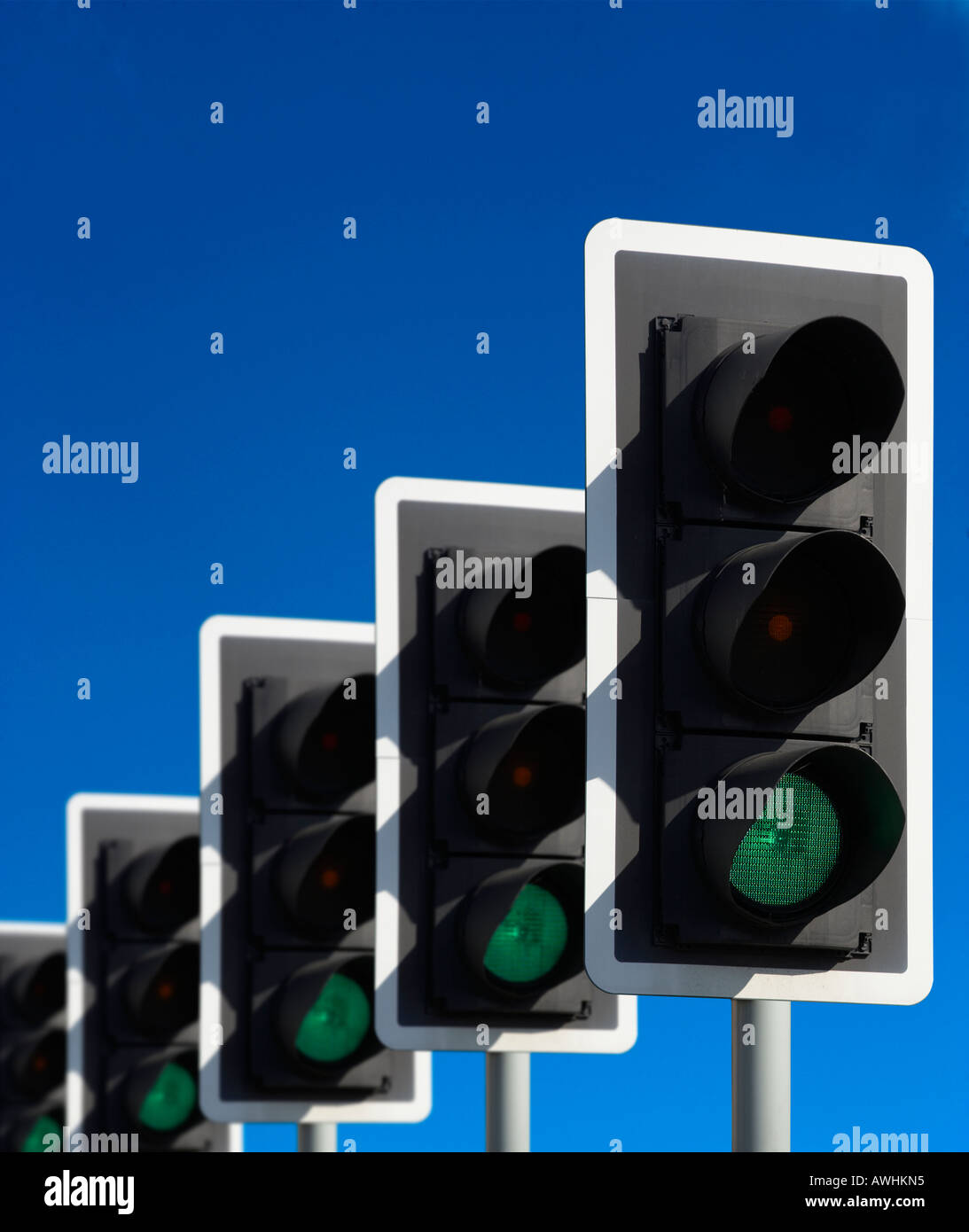 ROW OF FIVE ROAD TRAFFIC LIGHTS SHOWING GREEN WITH BLUE SKY Stock Photo