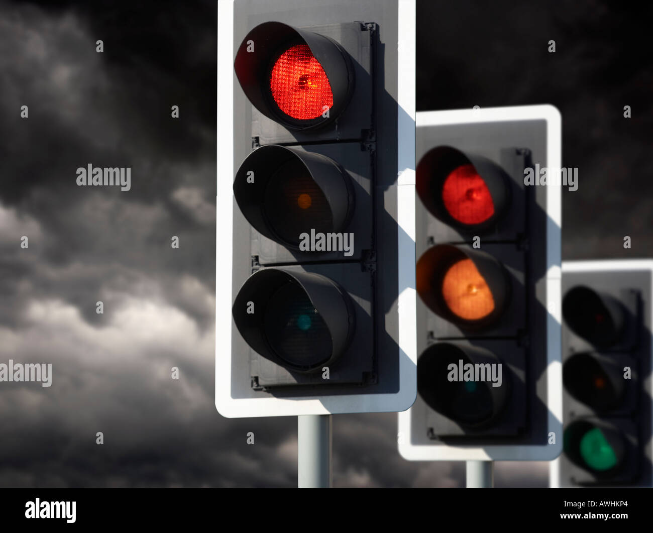 ROW OF THREE ROAD TRAFFIC LIGHTS SHOWING RED AMBER GREEN SEQUENCE WITH STORMY SKY Stock Photo