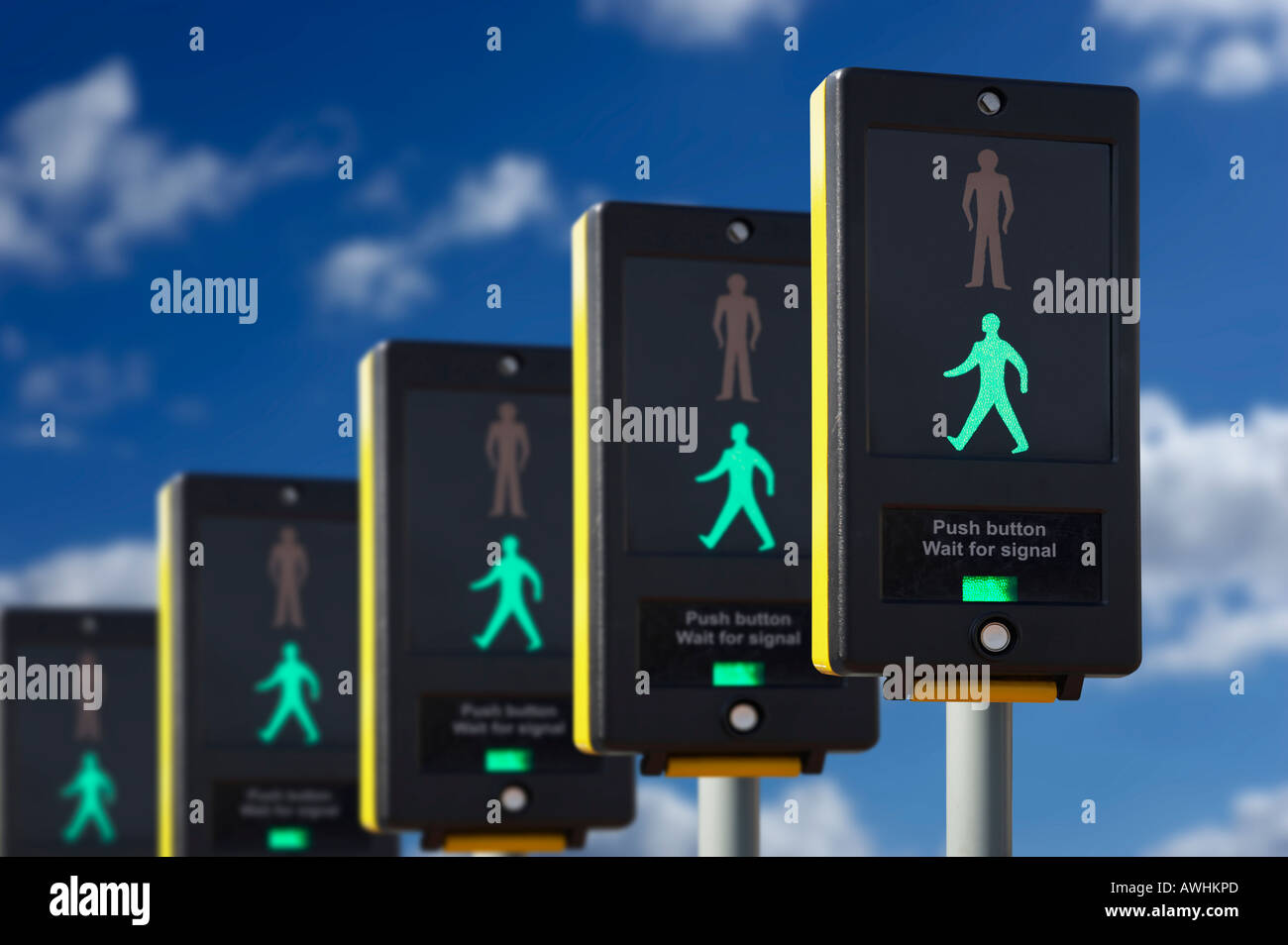 ROW OF FIVE PEDESTRIAN CROSSING CONTROL BOXES WITH ICON OF GREEN MAN ON BLUE SKY Stock Photo