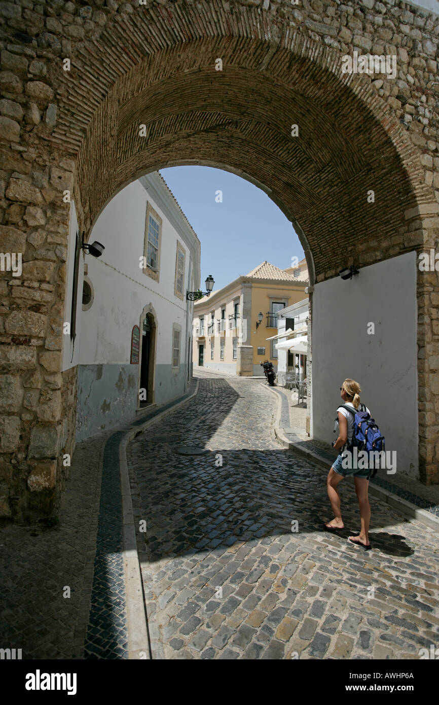 A woman walk through the arch entry into Cidade Velha or Velha citadel in Faro Portugal Stock Photo