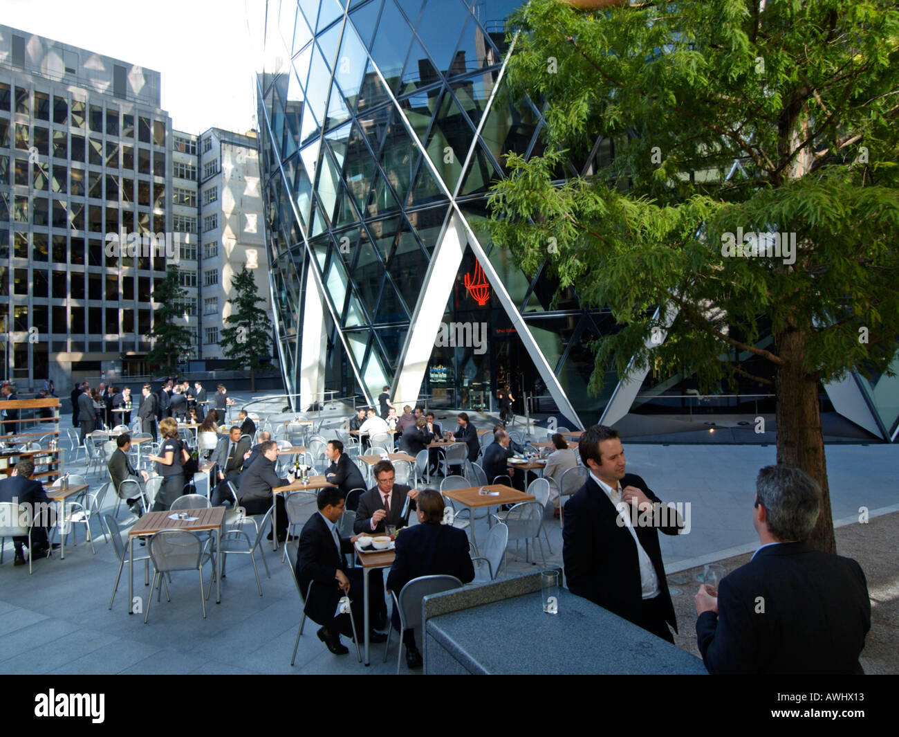 businessmen office workers having lunch lunchtime at the base of the Swiss Reinsurance building a k a the gherkin London UK Stock Photo
