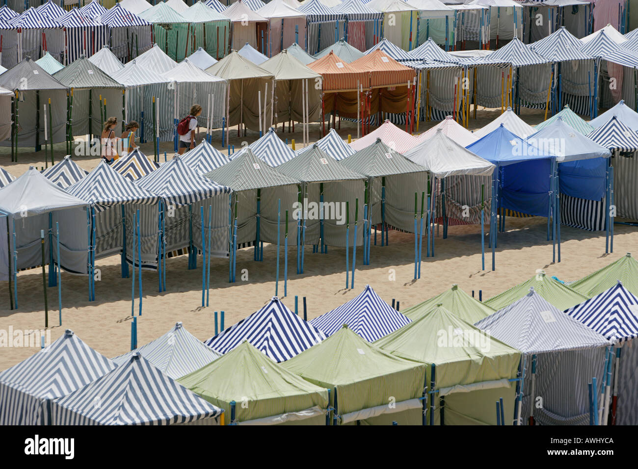 Beachgoers walk past seasonal cabanas on the wide beach of Nazare, Portugal. Stock Photo