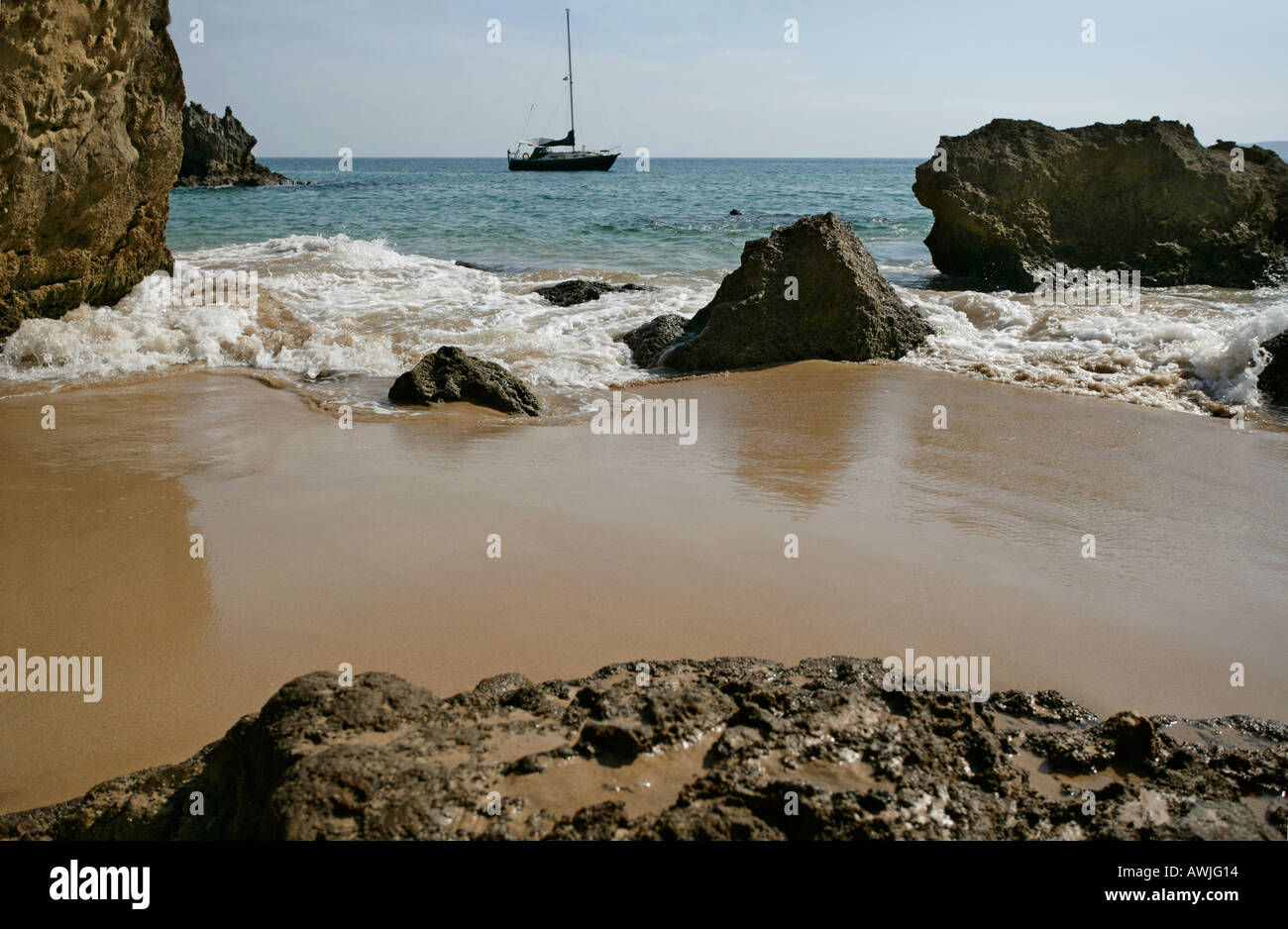 A cruising sailboat anchored off a secluded sandy beach This beach was off Portugals Algarve coast Stock Photo