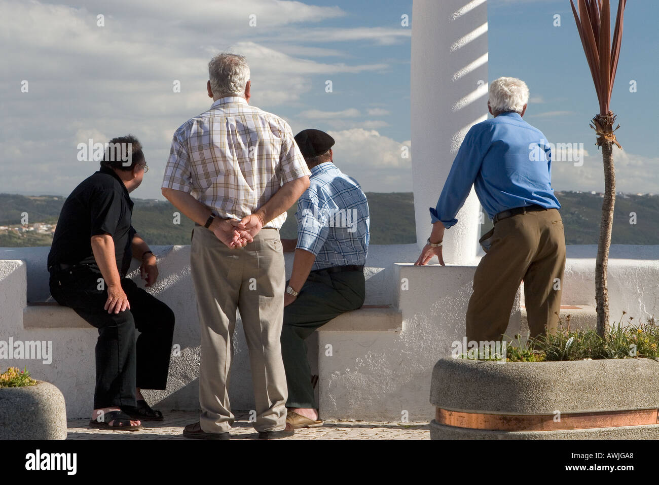 Four senior residents of Nazaré Portugal are intently watching something interesting from the Promontório do Sitio clifftop area Stock Photo
