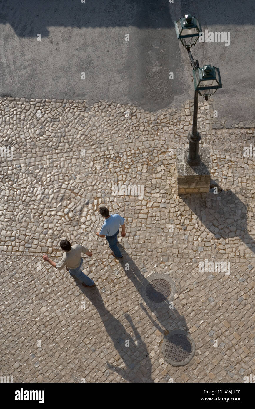 Two men walking on a cobbled plaza as seen from above Stock Photo