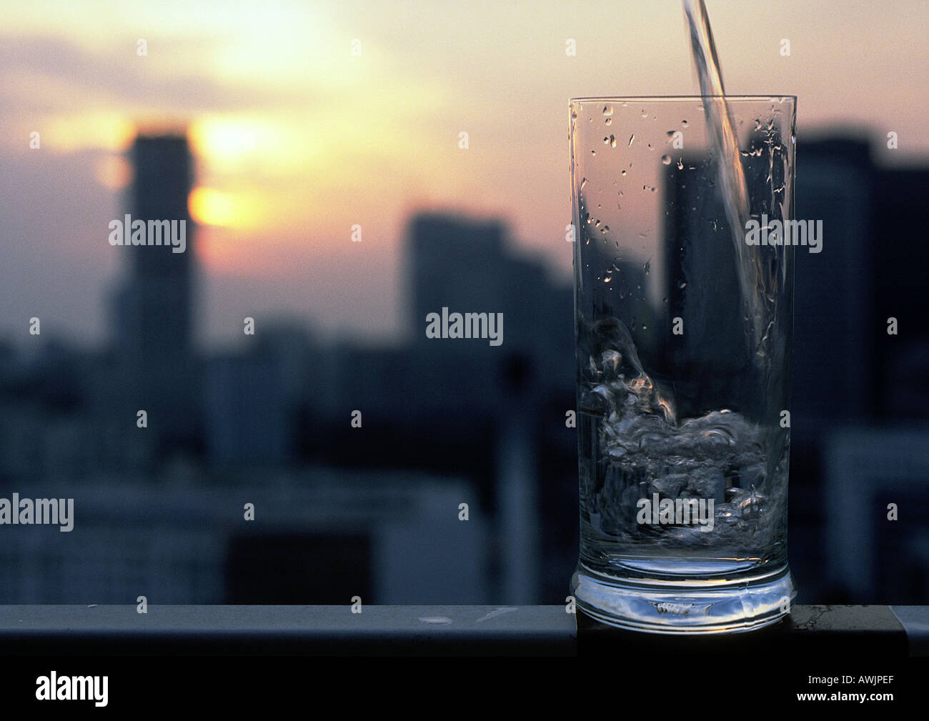 Glass with ice and straw in front of blurred cityscape Stock Photo