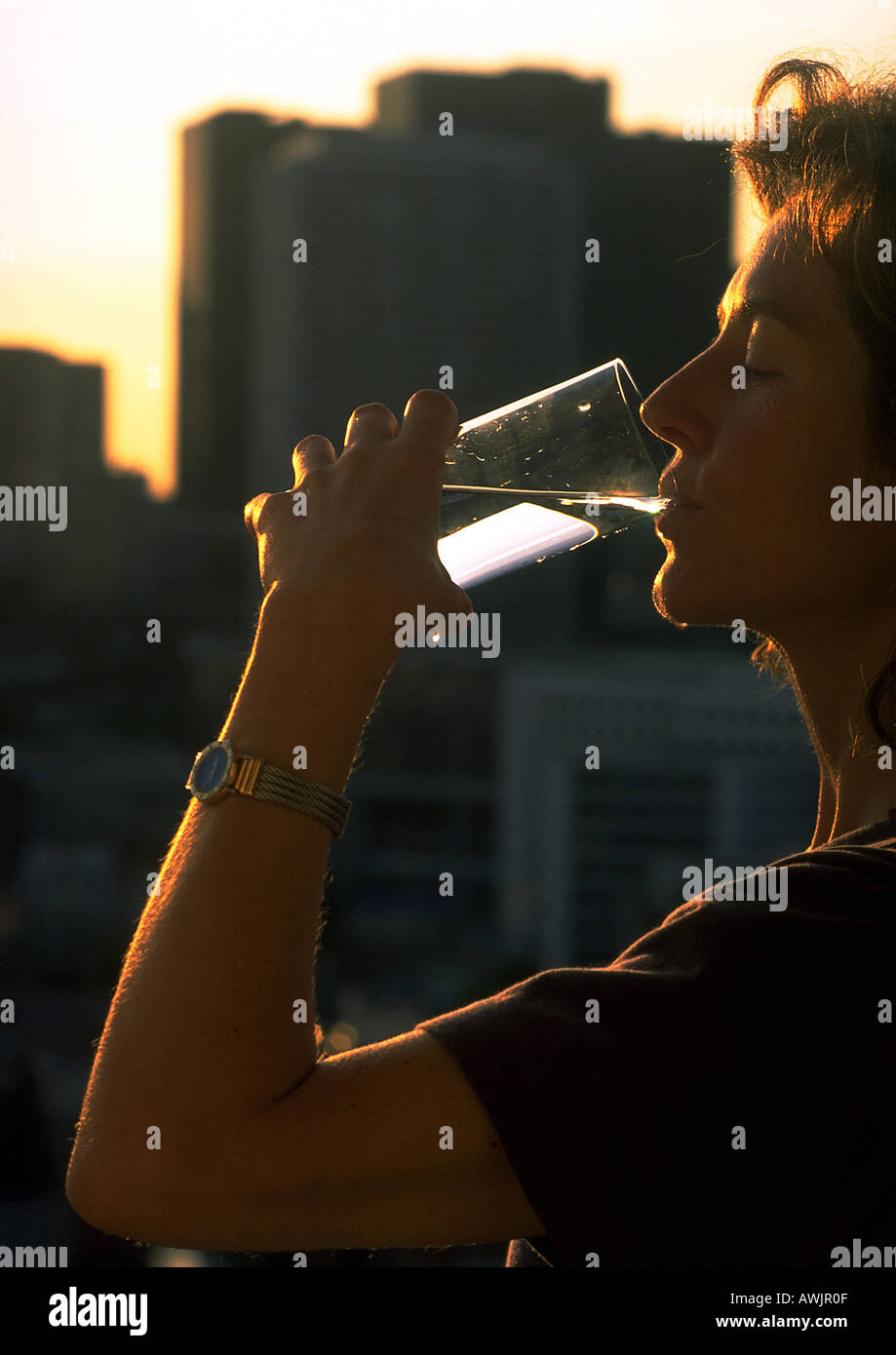 Woman drinking water, high rises in background Stock Photo
