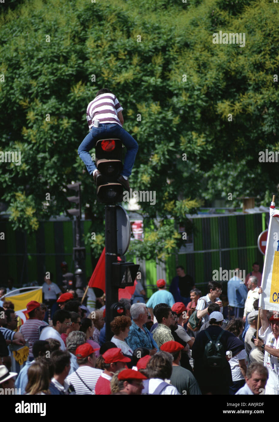 Man sitting on traffic light post in middle of crowd Stock Photo - Alamy
