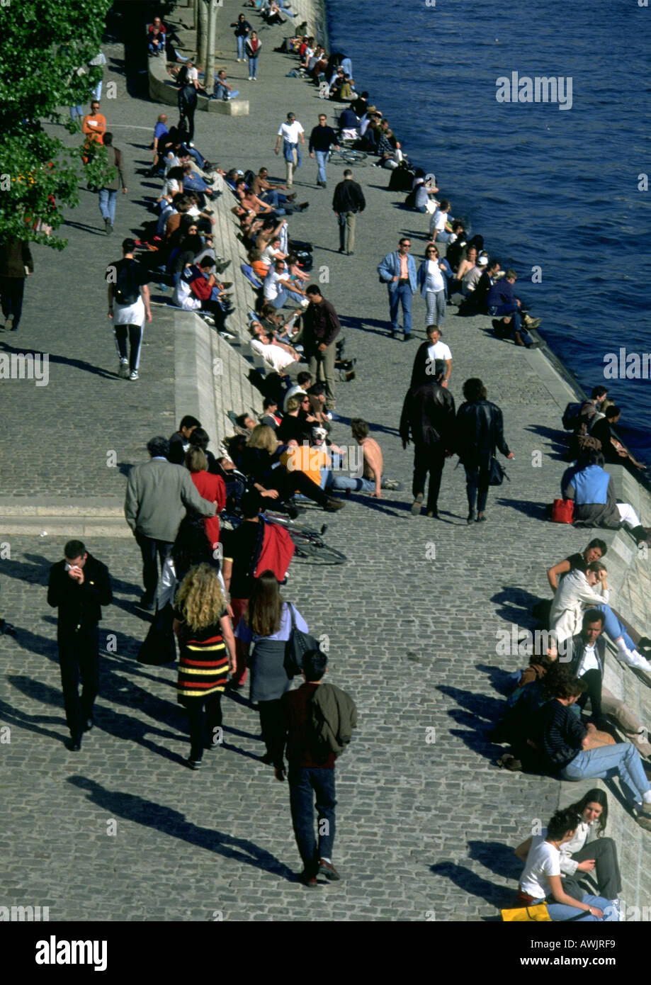 People walking and sitting by water Stock Photo