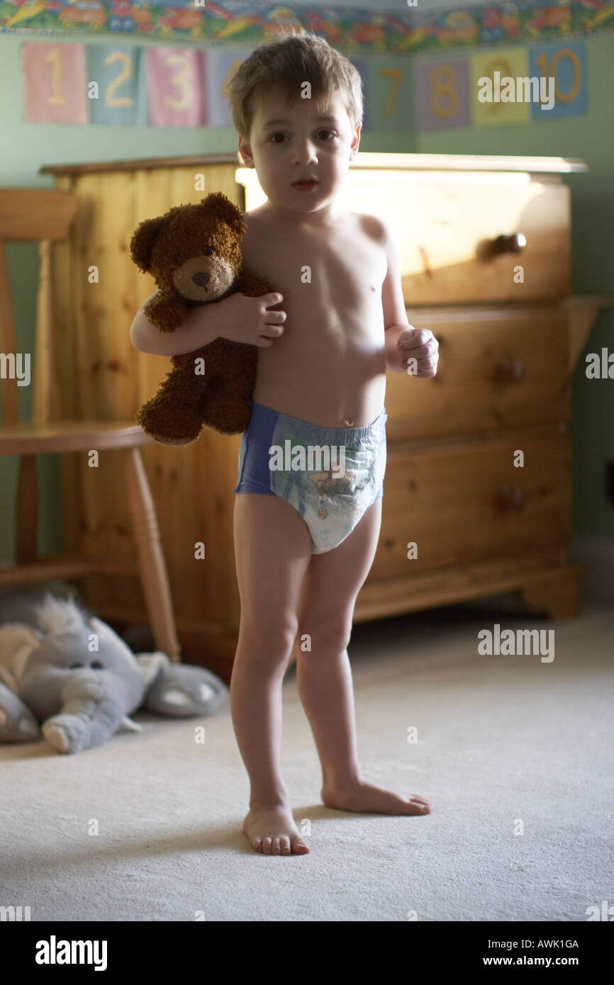 Young boy child standing in his bedroom with teddy bear wearing a pull up  nappy CJWH Stock Photo - Alamy