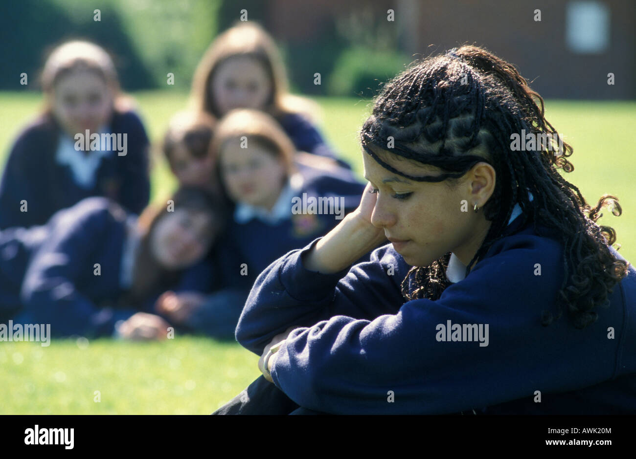 uniformed high school girl of mixed race origin tormented by group of peers in school playground