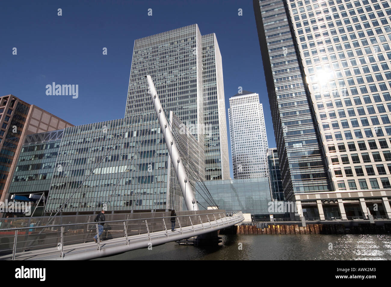 Canary Wharf tall modern office steel , glass skyscraper buildings with people on footbridge over West India Docks in Docklands Stock Photo