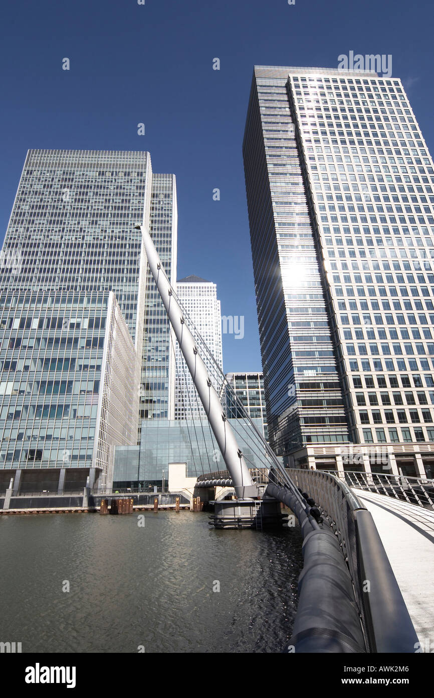 Canary Wharf tall modern office steel , glass skyscraper buildings with people on footbridge over West India Docks in Docklands Stock Photo