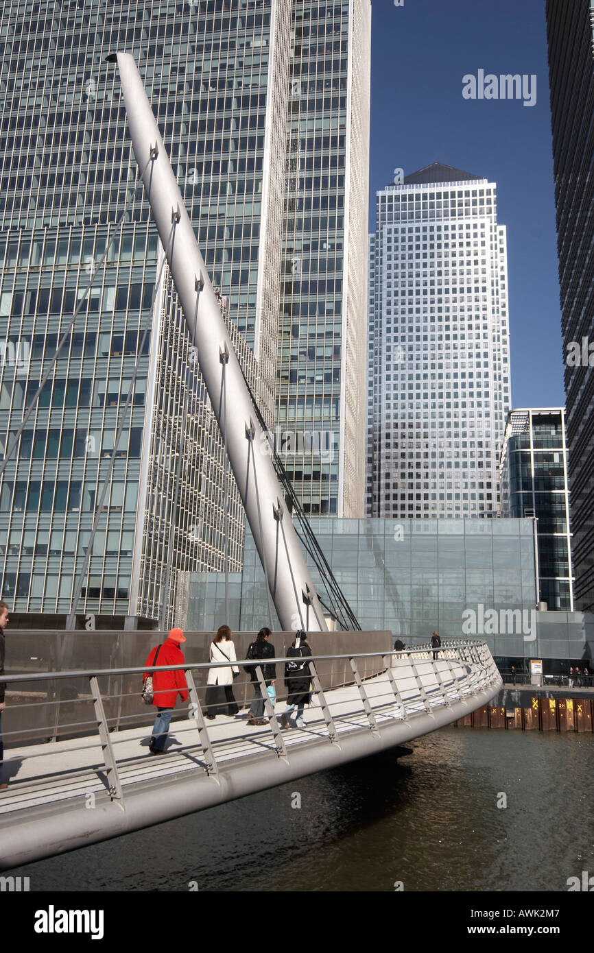 Canary Wharf tall modern office steel , glass skyscraper buildings with people on footbridge over West India Docks in Docklands Stock Photo