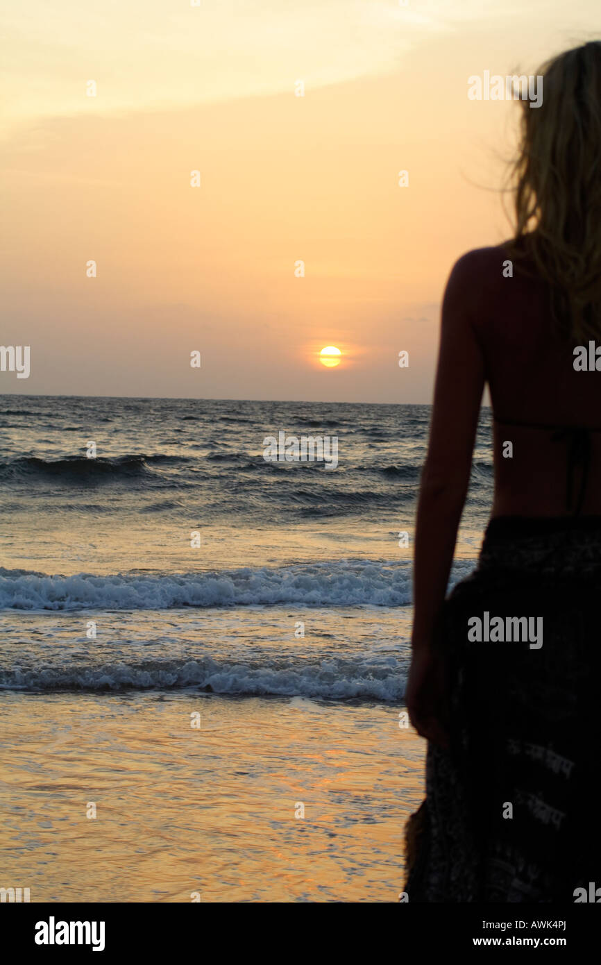 rear of woman standing by the sea with a beautiful sunset Stock Photo ...