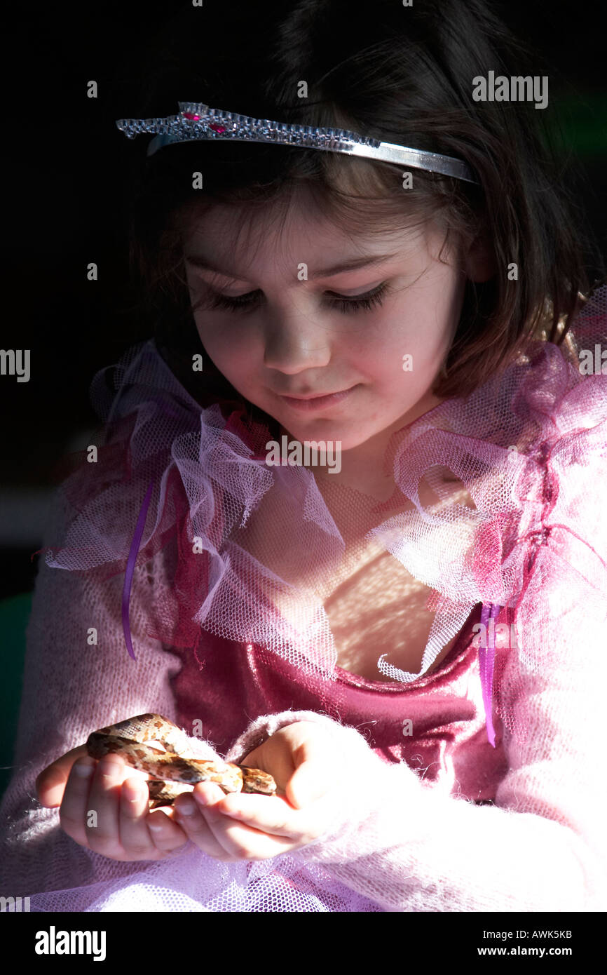 Young girl in princess costume holding a snake reptile at a children s educational birthday party in John Grooms FAITH Plant Cen Stock Photo