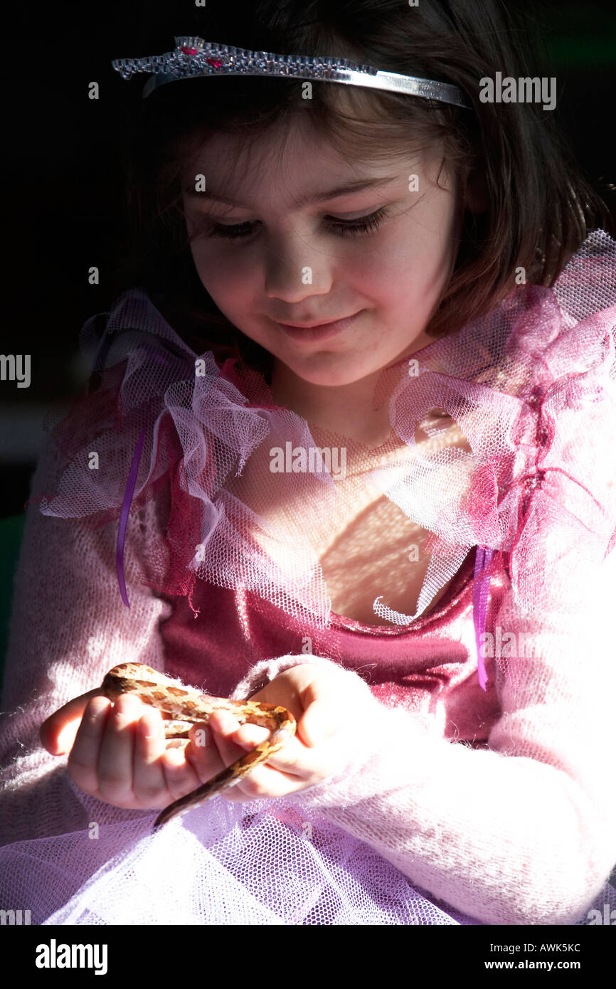 Young girl in princess costume holding a snake reptile at a children s educational birthday party in John Grooms FAITH Plant Cen Stock Photo