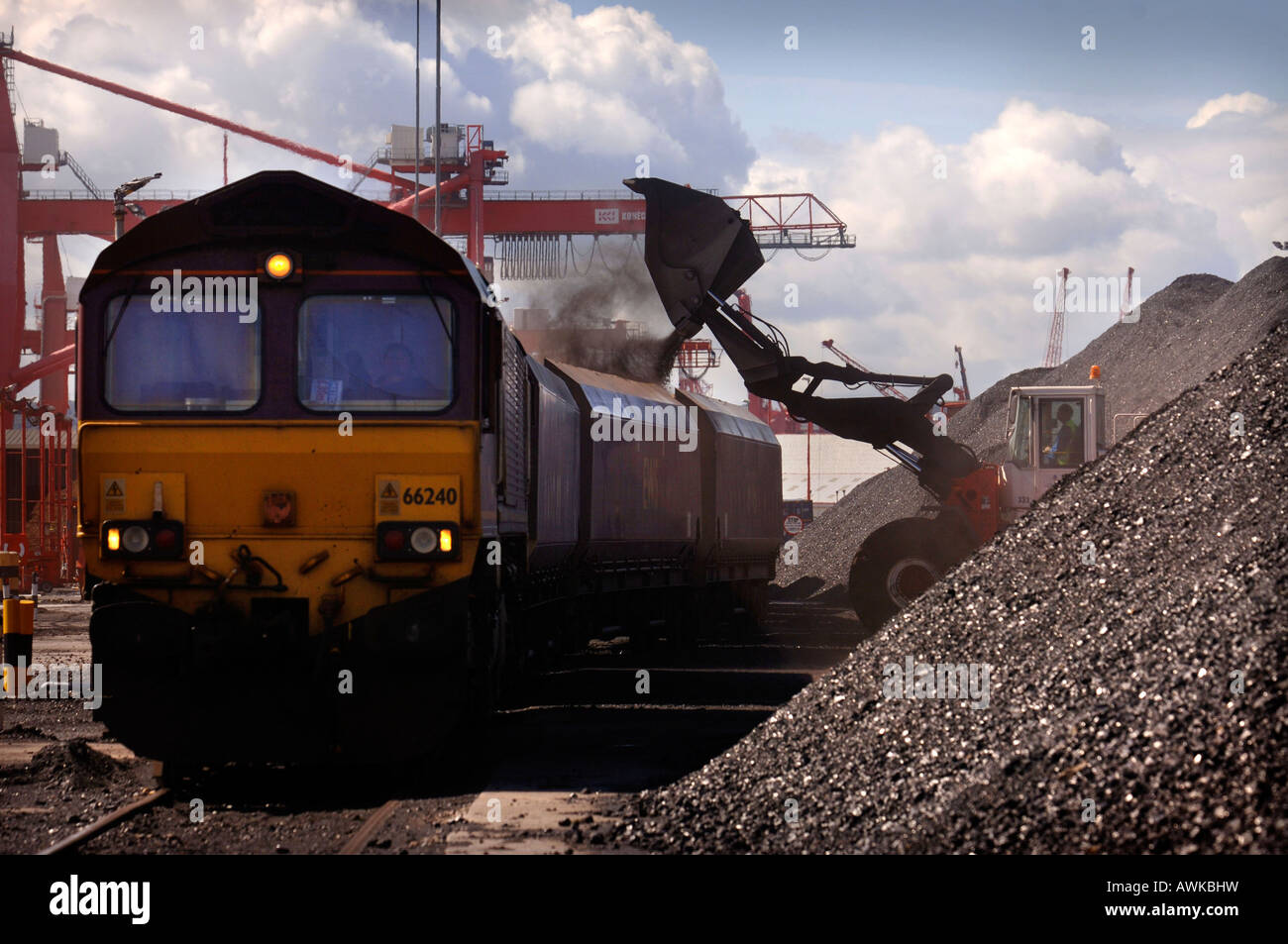 A MECHANICAL DIGGER LOADS IMPORTED COAL ONTO RAILWAY TRUCKS AT AVONMOUTH DOCKS UK Stock Photo
