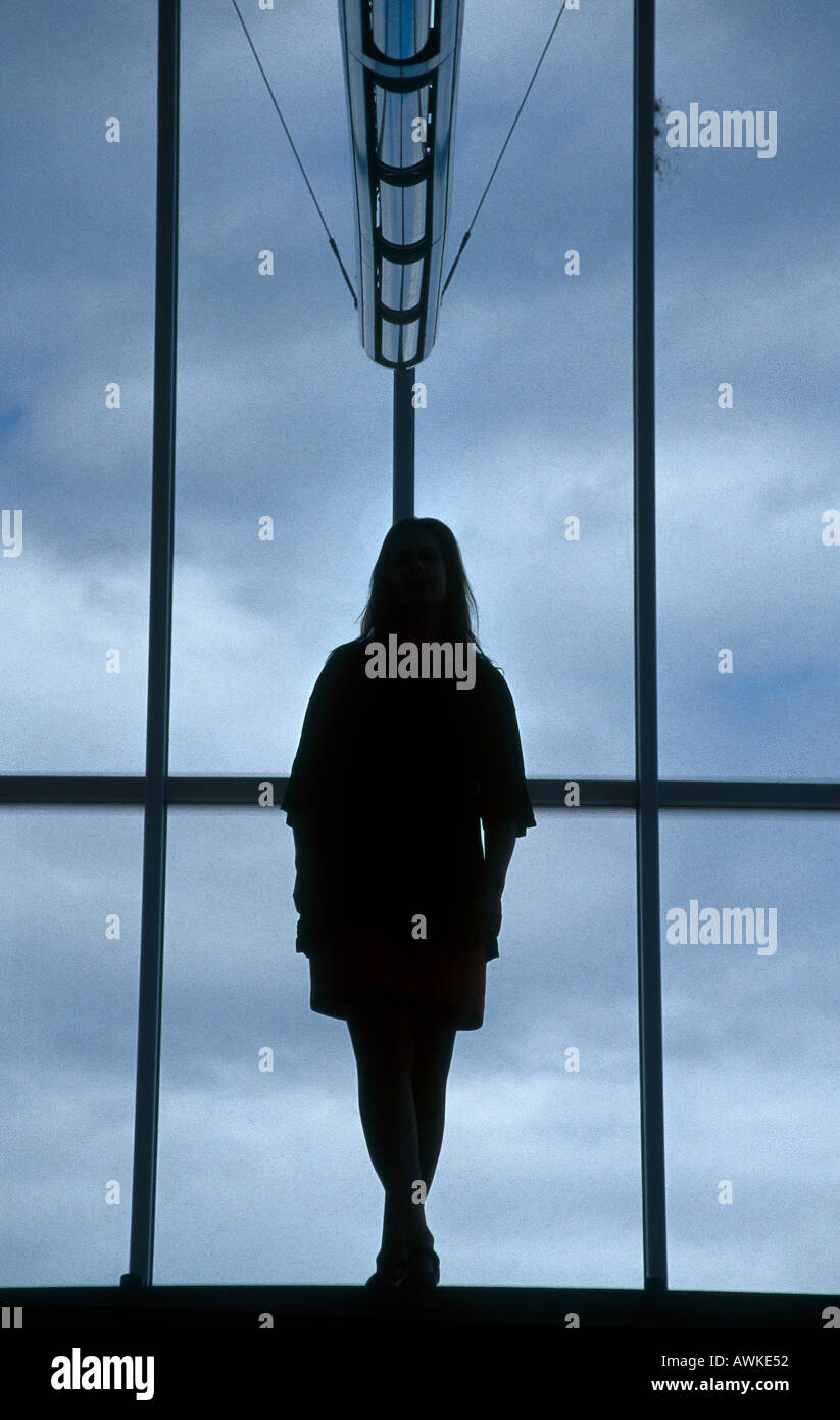 Silhouette of young woman standing in front of window Stock Photo