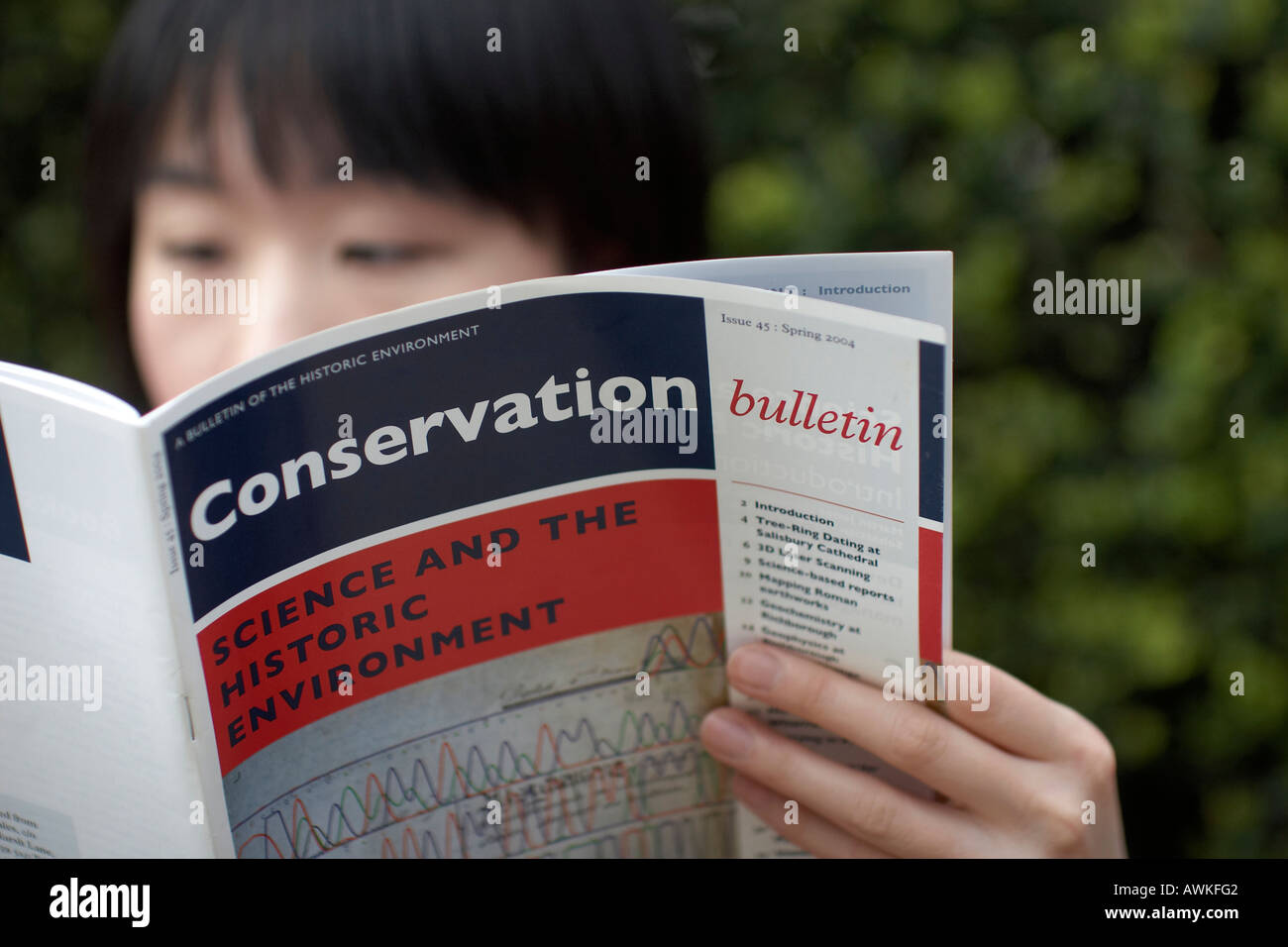 Asian woman reading an English Heritage Conservation bulletin Shalllow depth of field or focus Stock Photo