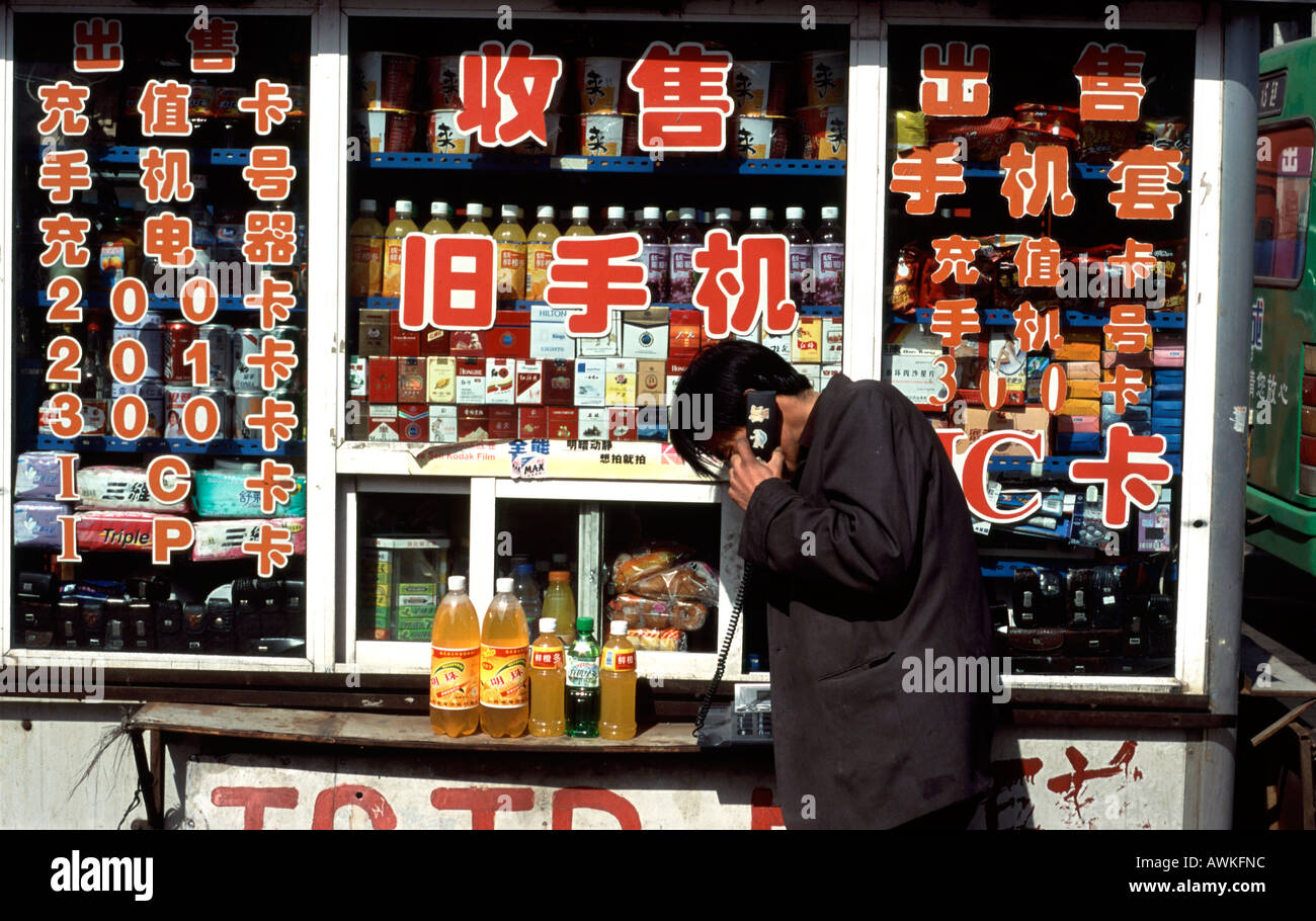 A Man uses telephone at street stall in Datong city in Shanxi Province, China Stock Photo