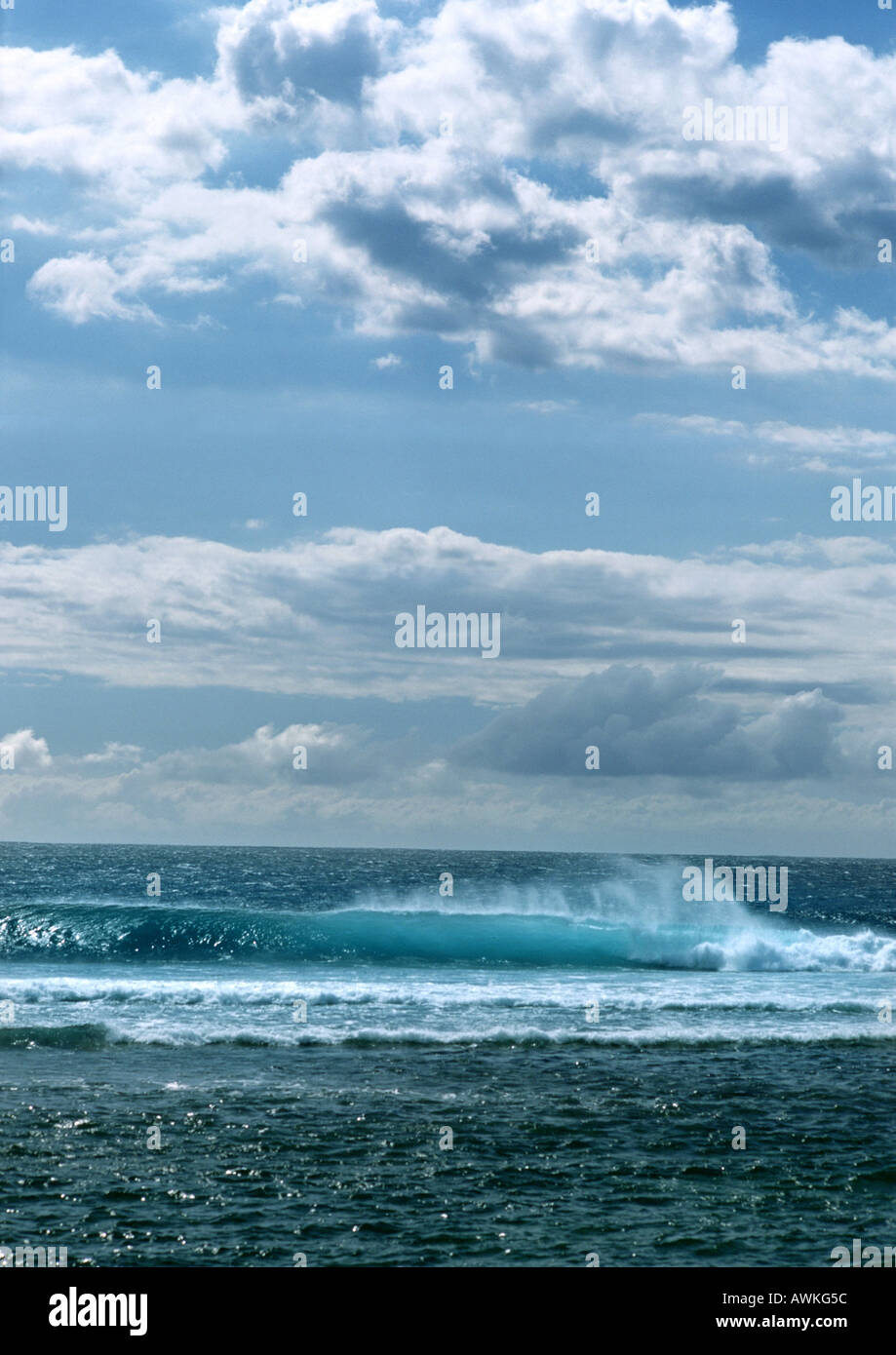 Wave crashing in ocean under blue sky with clouds Stock Photo - Alamy