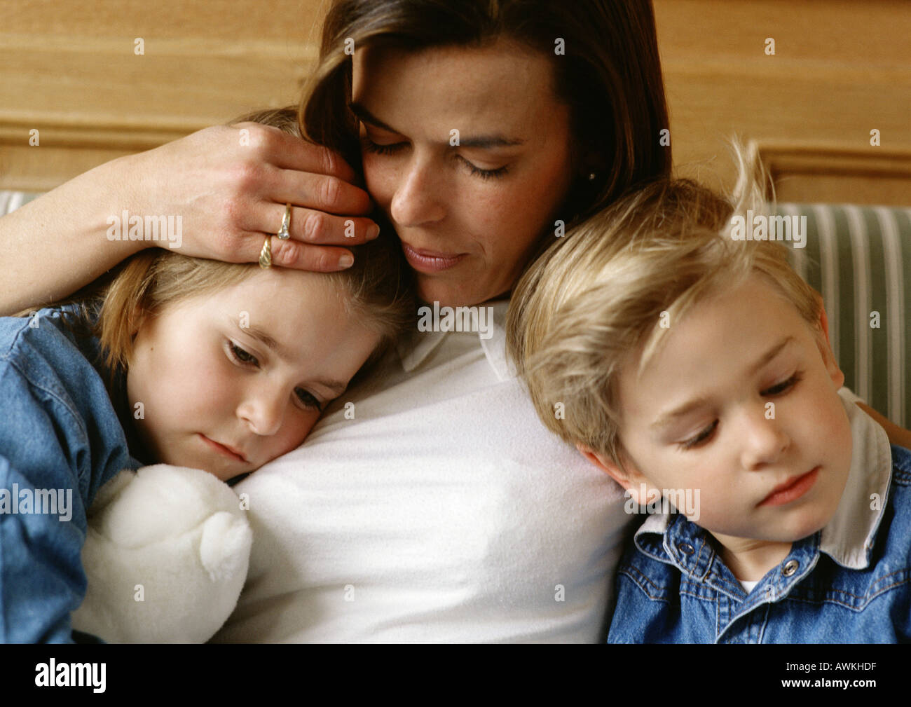 Woman between two children, holding little girl's head to her chest, little boy leaning against her, close-up Stock Photo