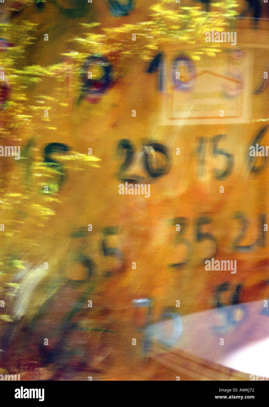 Handwritten numbers behind glass with reflection, blurry. Stock Photo