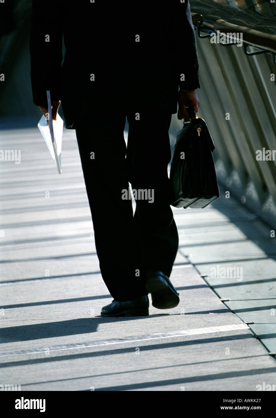 Business man carrying briefcase, waist down, rear view Stock Photo