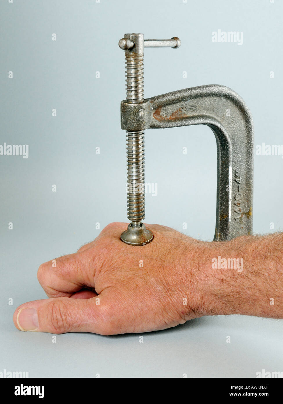 Hand clamped in a vise denoting arthritic pain Stock Photo