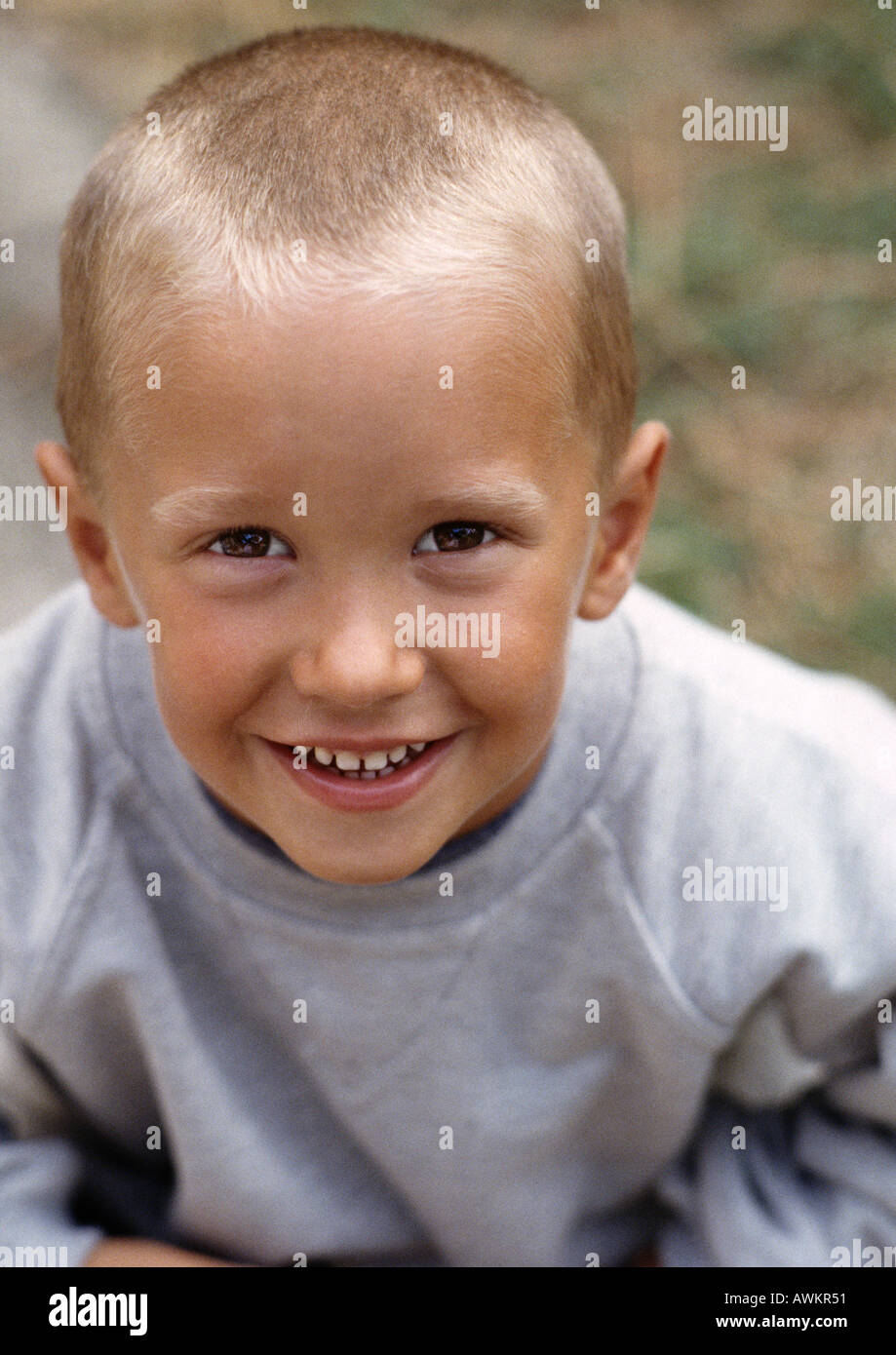Young boy with short fair hair, wearing grey sweatshirt, smiling, high angle view, portrait Stock Photo