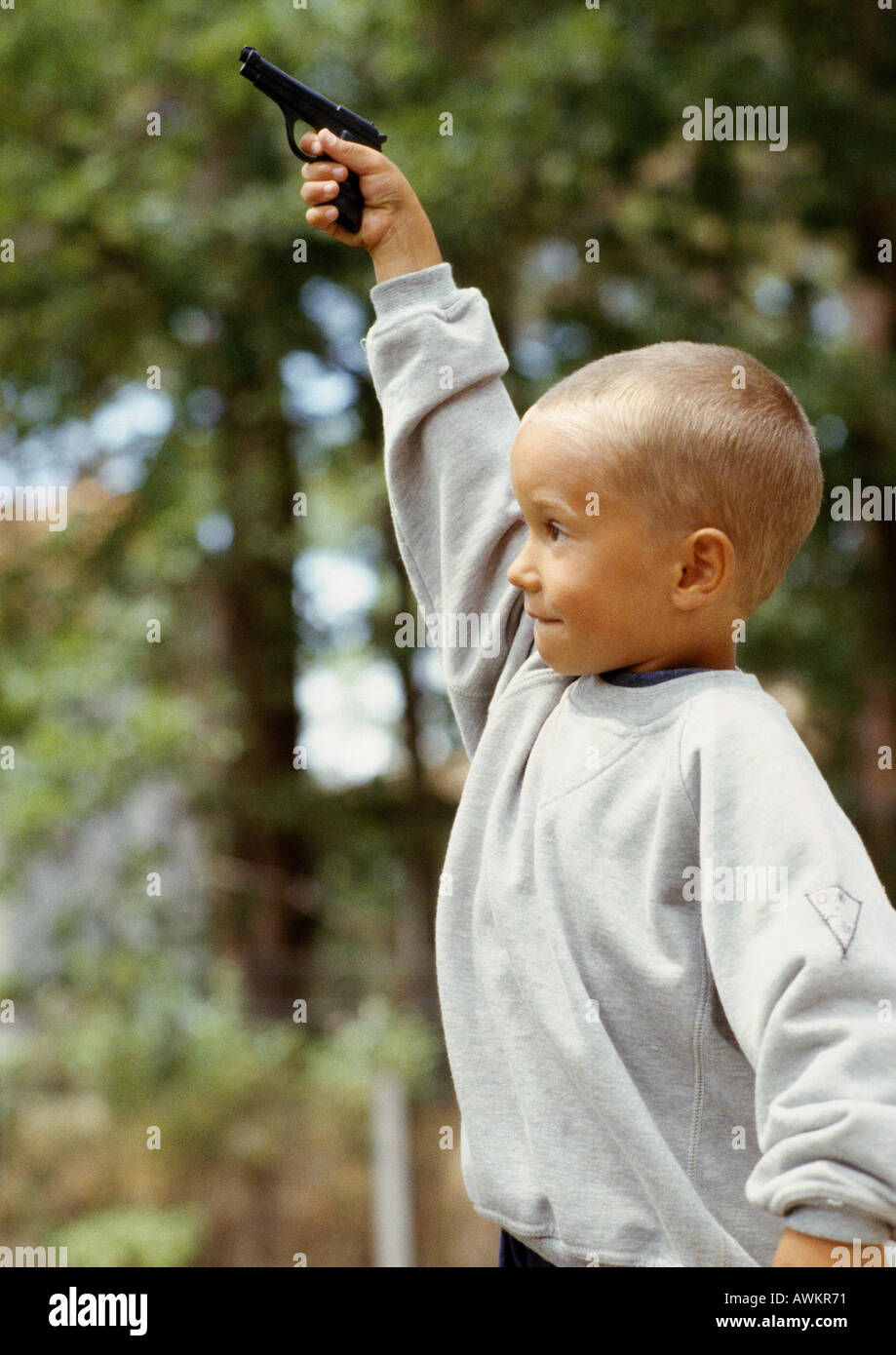Boy holding toy gun, outside, rear view Stock Photo