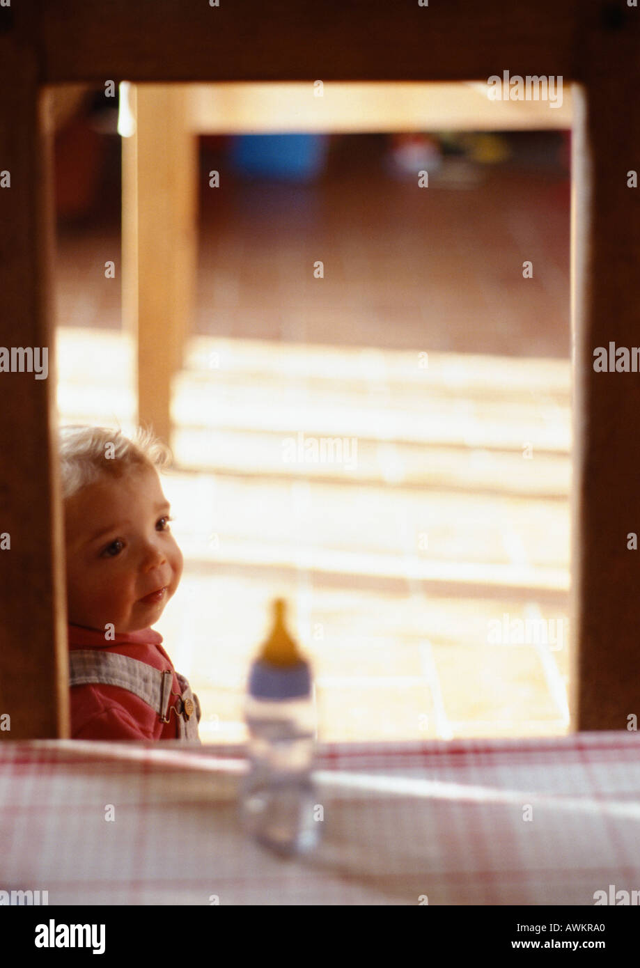 Toddler in a room, blurred baby's bottle in foreground Stock Photo