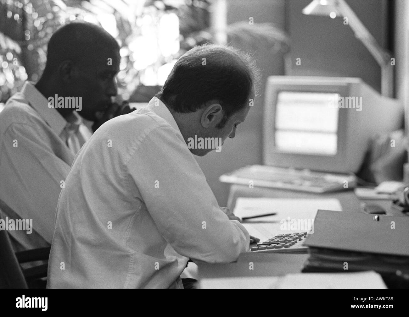 Two men sitting at desk, b&w Stock Photo