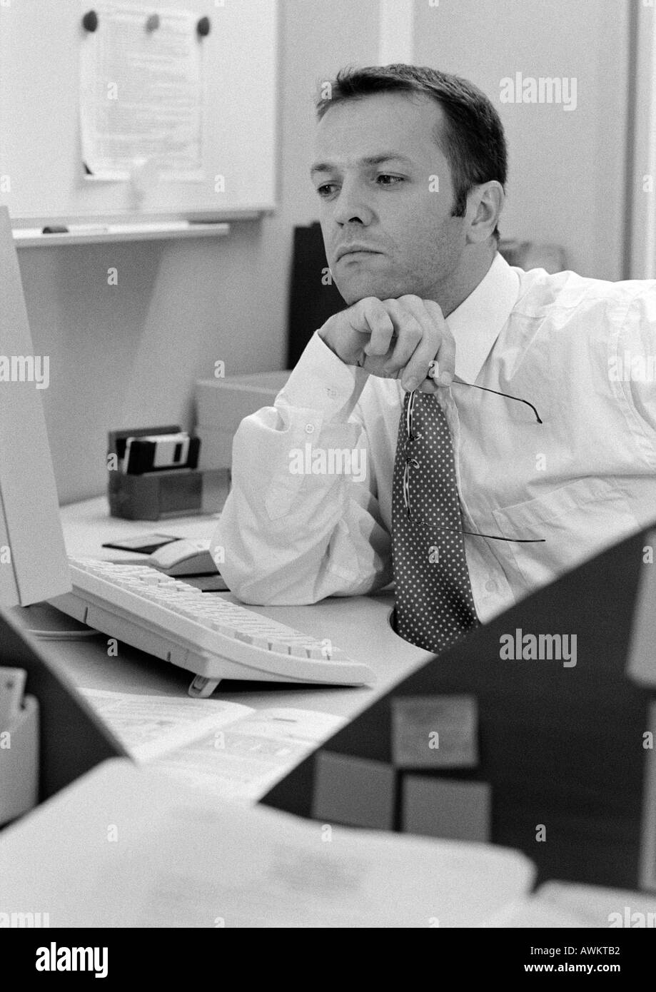 Man sitting at desk, elbow on table, b&w Stock Photo