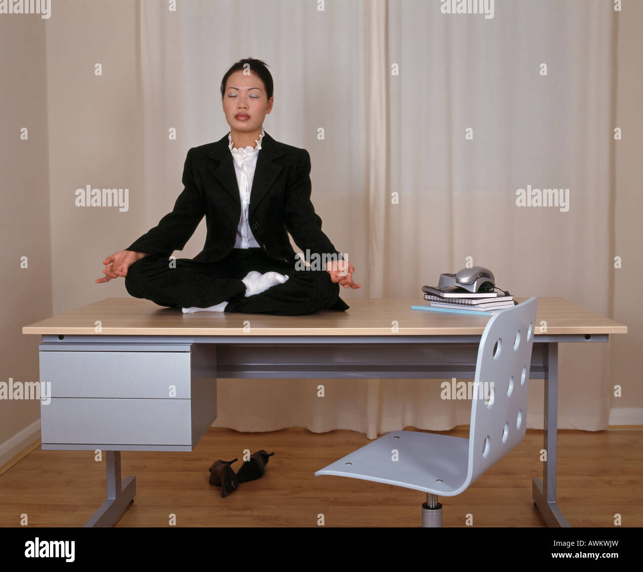 Young woman practising yoga on office desk Stock Photo