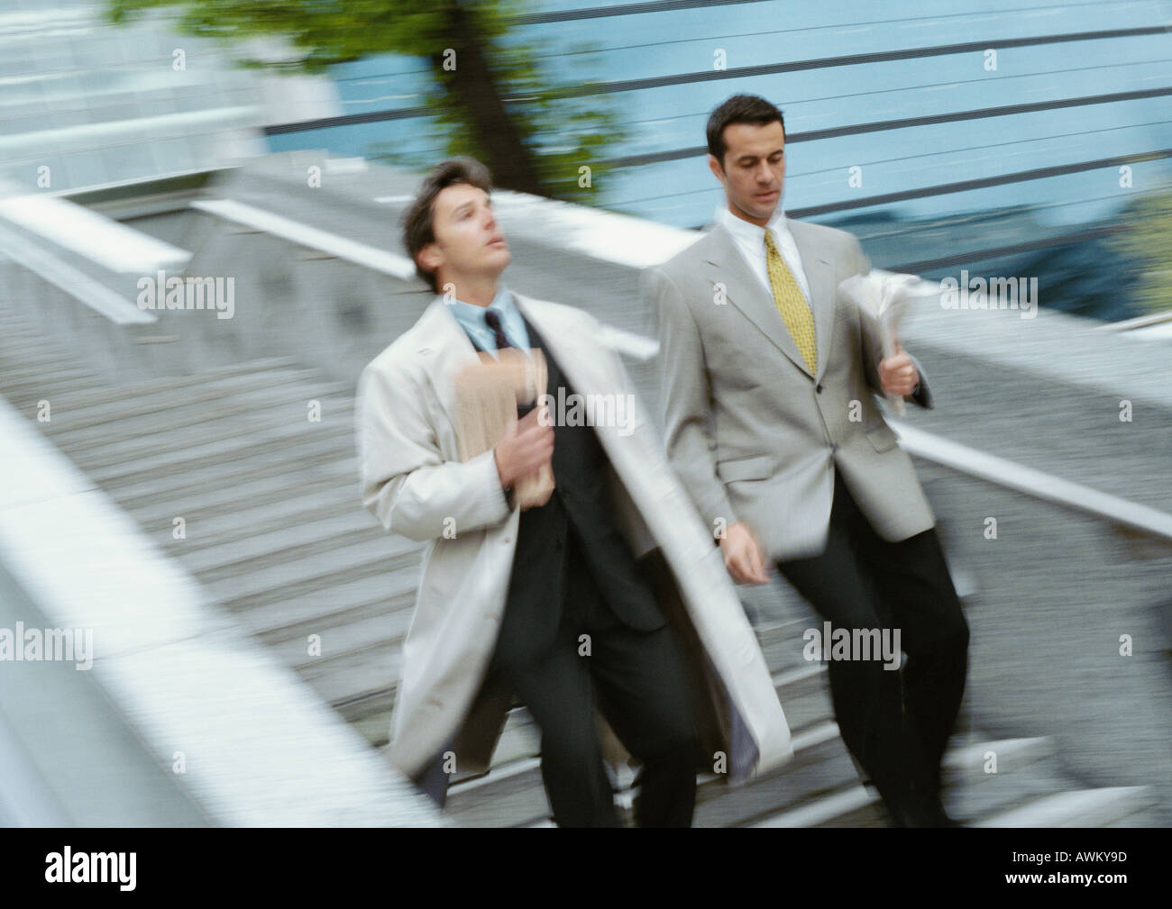 Two businessmen going down stairs side by side, blurred Stock Photo