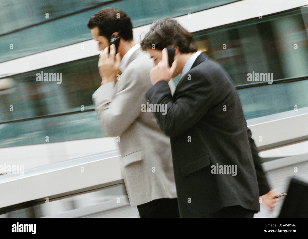 Two businessmen using cell phones outside, side view Stock Photo