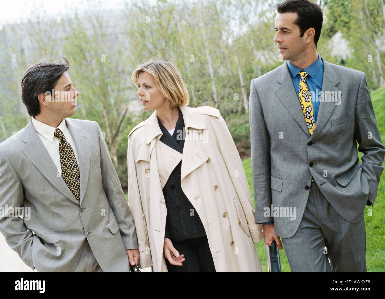 Three business people walking side by side in park Stock Photo