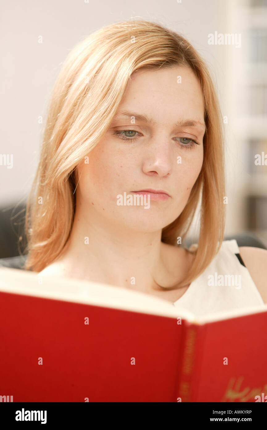 Blonde woman reading in a red book Stock Photo - Alamy