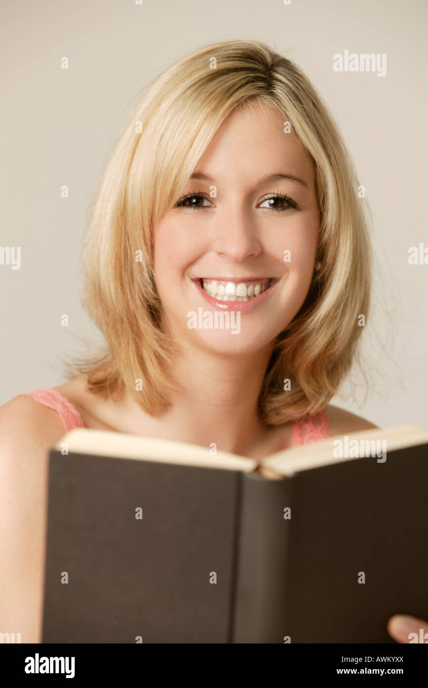 Smiling young blonde woman reading a book Stock Photo - Alamy