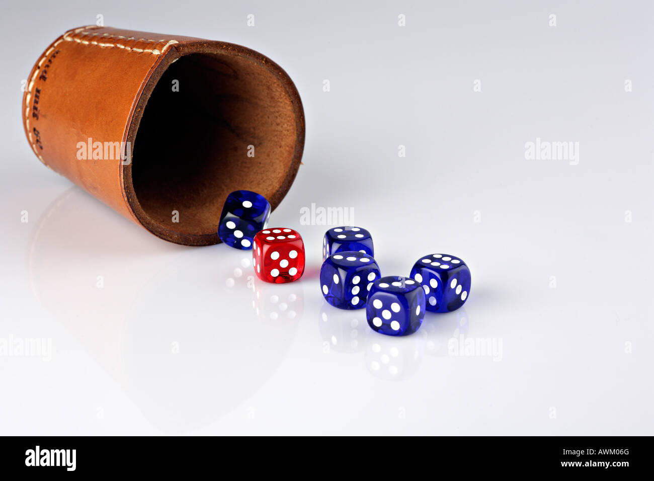 Five blue and one red dice beside a dice cup Stock Photo